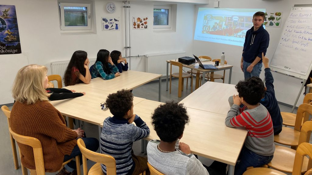 Kinder schauen auf eine Leinwand mit einer Präsentation zum Thema Kinderrechte