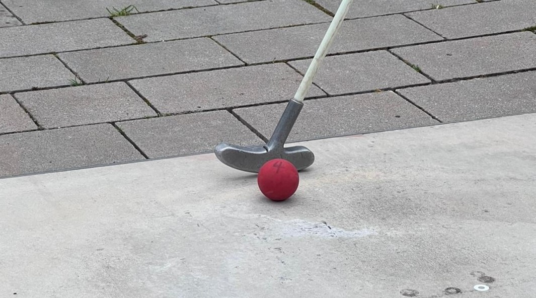 Ein roter Minigolfball vor einem Schäger