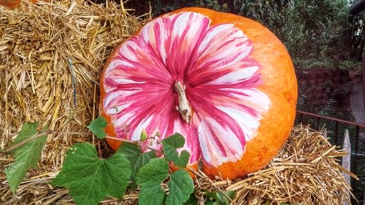 Kürbis, bemalt mit einer Blume, auf Heuballen