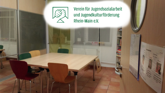 Der Raum für die Hausaufgabenhilfe hat einen großen Tisch mit mehreren Stühlen, es gibt große Fenster mit Vorhängen und ein Regal mit Büchern.